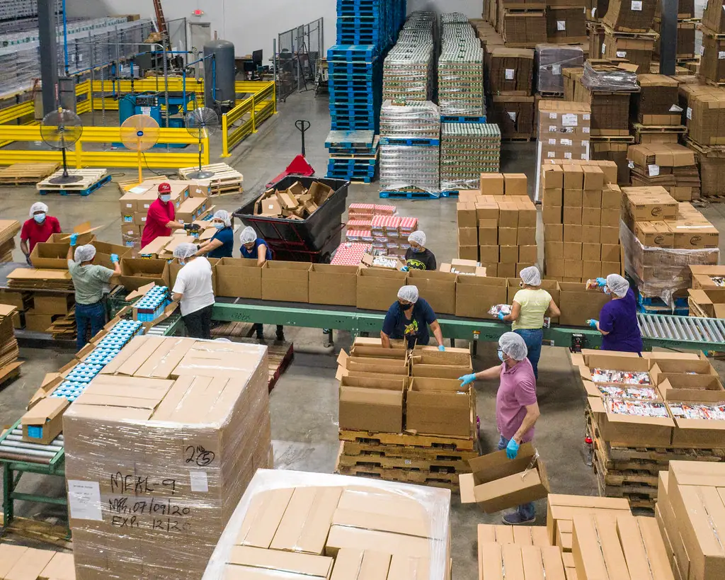 Workers packing goods into cartons on a busy factory floor