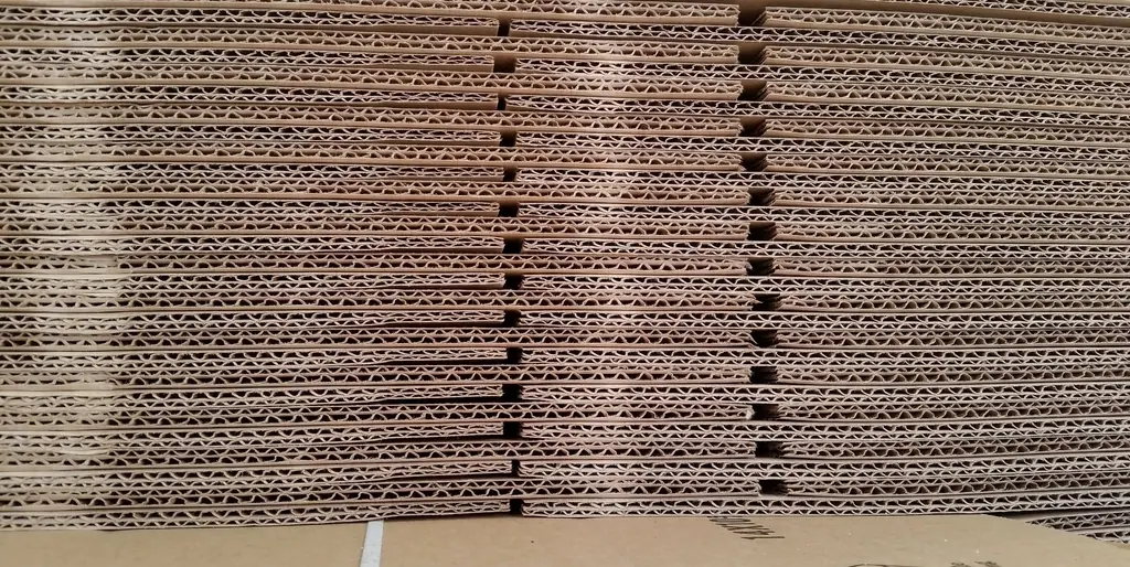 A tall stack of flat corrugated sheets seen from the edge